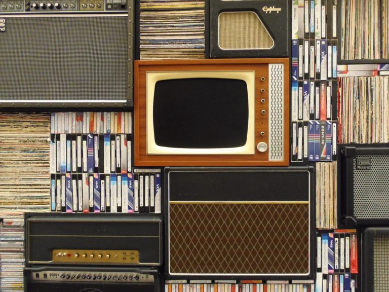 an old TV surrounded by VHS tapes